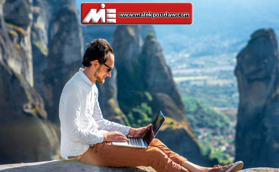 Well dressed man working with laptop sitting on the rocky mountain on beautiful scenic clif background near Meteora monasteries in Greece.